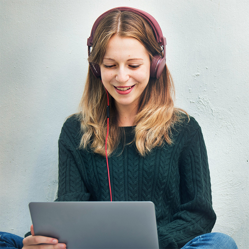 A woman wearing headphones using a laptop